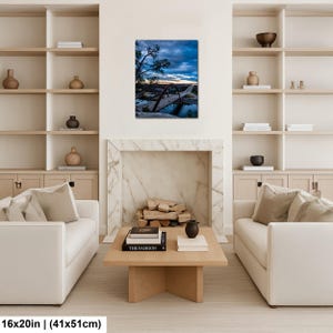 May include: A rectangular wall art print featuring a landscape photograph of a red arched bridge spanning a river at dusk. The sky is filled with dark blue clouds and a hint of sunset light. The print measures 16 inches by 20 inches in size.