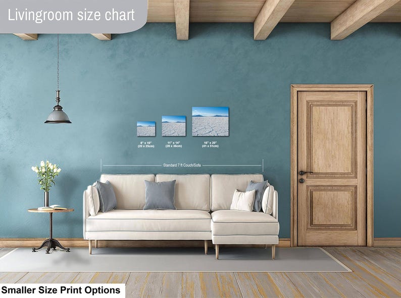 May include: A living room size chart showing three rectangular wall art prints above a cream-colored sectional sofa. The prints display a dry cracked landscape under a blue sky, with sizes labeled as 8x10 inches, 11x14 inches, and 16x20 inches.