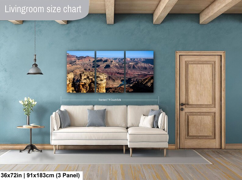May include: A three-panel wall art set depicting a Grand Canyon landscape with rocky cliffs and a blue river, displayed above a cream-colored sectional sofa. The text "Livingroom size chart" and "36x72in | 91x183cm (3 Panel)" appear on the image.