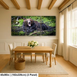 May include: A three-panel wall art set featuring a brown bear lying in a grassy, mossy area with its mouth open. The artwork measures 40 by 90 inches in total, displayed as three separate panels showing the bear in a natural environment.