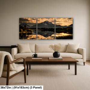 Puede incluir: Un conjunto de arte mural de tres paneles que representa un paisaje monta&ntilde;oso al atardecer con nubes doradas reflejadas en la superficie de un lago tranquilo. La obra mide 91 cm por 183 cm y muestra siluetas oscuras de &aacute;rboles y cumbres.