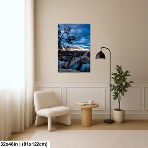 May include: A rectangular wall art print measuring 32 by 48 inches, featuring a landscape photograph of a large arched bridge spanning a body of water under a dramatic, dark blue cloudy sky at dusk, with silhouetted trees in the foreground.