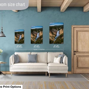 May include: A living room size chart displaying three vertical wall art prints of a waterfall in a canyon, with dimensions of 16 x 24 inches, 20 x 30 inches, and 24 x 36 inches, positioned above a white sectional sofa with gray and white pillows.