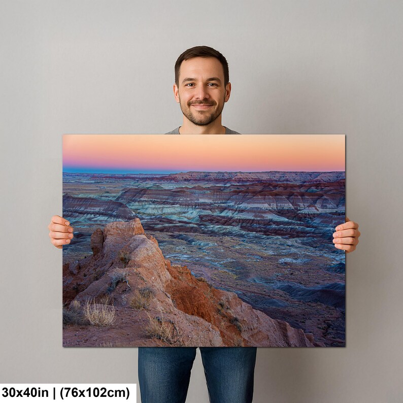 May include: A rectangular landscape wall art print measuring 30 by 40 inches, featuring a desert canyon at sunset with layered rock formations in shades of orange, blue, and grey under a soft pink and orange gradient sky with sparse vegetation.