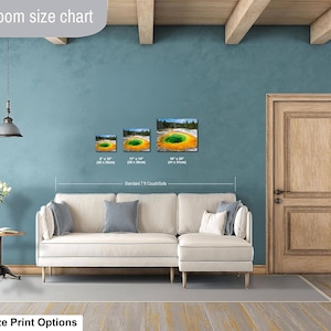 May include: A living room size chart displaying three landscape-oriented wall art prints of the Grand Prismatic Spring in Yellowstone. The prints are shown in sizes 8x10 inches, 11x14 inches, and 16x20 inches, positioned above a standard 7-foot couch.