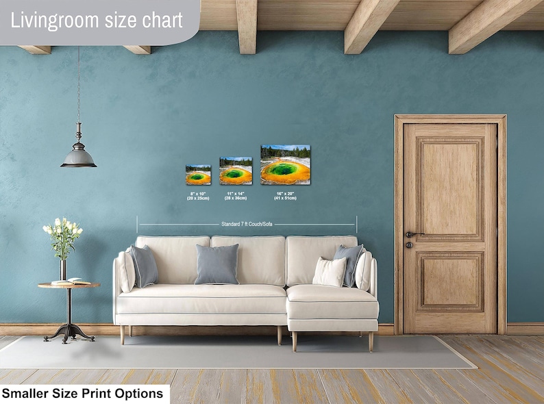 May include: A living room size chart displaying three landscape-oriented wall art prints of the Grand Prismatic Spring in Yellowstone. The prints are shown in sizes 8x10 inches, 11x14 inches, and 16x20 inches, positioned above a standard 7-foot couch.