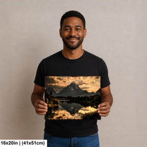 Puede incluir: Una impresi&oacute;n de arte mural rectangular de 41 por 51 cm, que presenta una fotograf&iacute;a de paisaje de una cadena monta&ntilde;osa reflejada en un lago tranquilo al atardecer, con luz dorada iluminando las nubes y siluetas oscuras de &aacute;rboles.