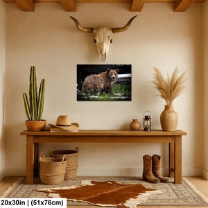 May include: A rectangular wall art print featuring a brown bear standing in a grassy field with light snowfall. The print measures 51 by 76 cm and is displayed on a wall above a wooden console table with various decorative items.