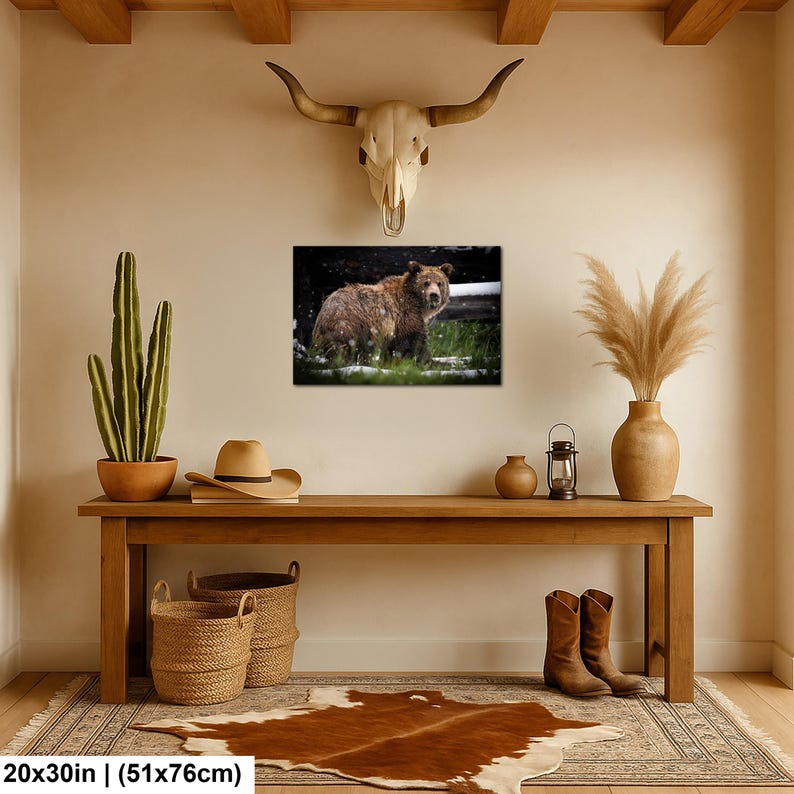 May include: A rectangular wall art print featuring a brown bear standing in a grassy field with light snowfall. The print measures 51 by 76 cm and is displayed on a wall above a wooden console table with various decorative items.