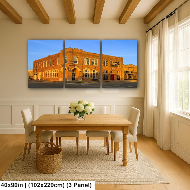 May include: A three-panel wall art set depicting a historic orange brick building under a clear blue sky. The artwork measures 40 by 90 inches in total. The scene features arched windows and architectural details of a multi-story commercial structure.