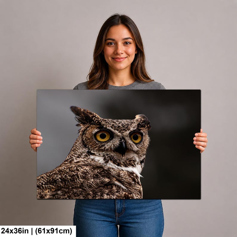 May include: A rectangular wall art print measuring 24 inches by 36 inches, featuring a high-resolution close-up photograph of a great horned owl. The owl has prominent yellow eyes, a dark beak, and detailed brown and tan mottled feathers.