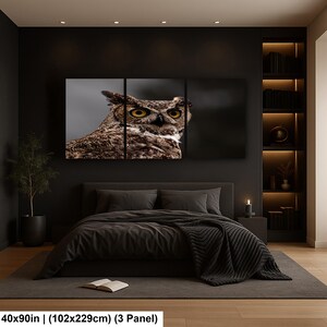 May include: A three-panel wall art set featuring a close-up photograph of a brown and white owl with large yellow eyes. The artwork measures 40 by 90 inches and is displayed above a bed in a dark room with integrated shelving and lighting.