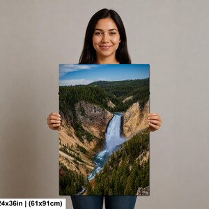 May include: A rectangular wall art print measuring 24 inches by 36 inches, featuring a landscape photograph of a waterfall cascading into a deep canyon surrounded by dense green pine forests, rocky cliffs, and a clear blue sky above.