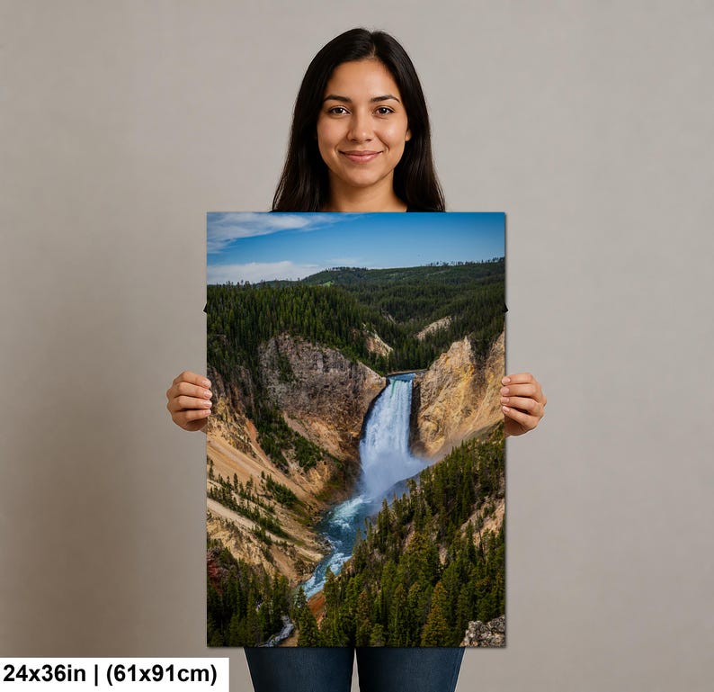 May include: A rectangular wall art print measuring 24 inches by 36 inches, featuring a landscape photograph of a waterfall cascading into a deep canyon surrounded by dense green pine forests, rocky cliffs, and a clear blue sky above.