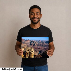 May include: A rectangular wall art print featuring a scenic landscape of the Grand Canyon with layered rock formations, deep shadows, and a blue sky. The print measures 16 inches by 20 inches and displays natural earth tones and blue hues.