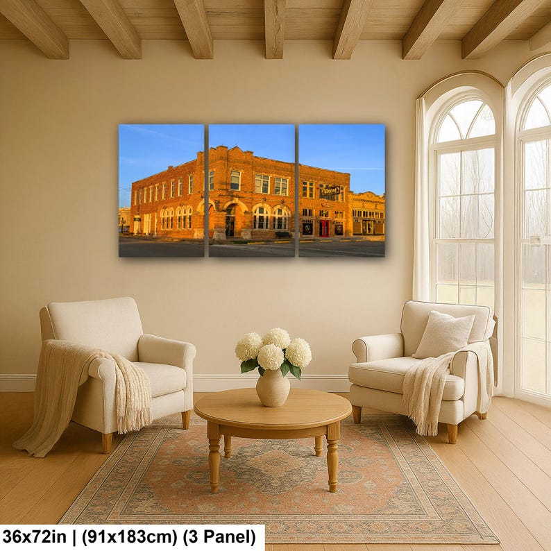 May include: A three-panel wall art set depicting a historic brick building under a clear blue sky. The artwork measures 36 inches by 72 inches. The scene features a multi-story structure with arched windows and warm golden lighting on the facade.