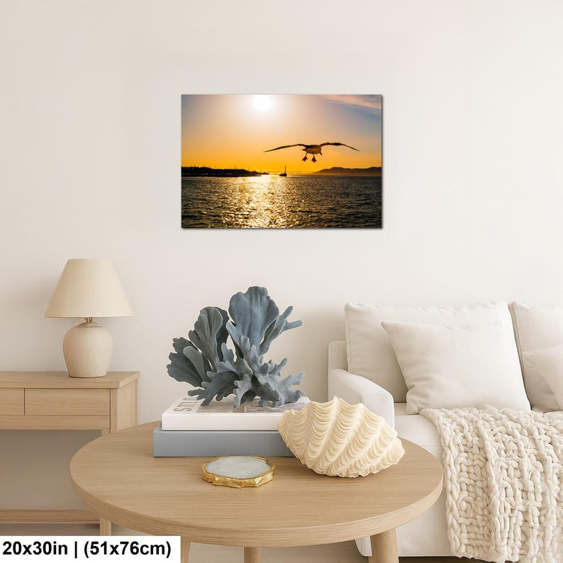 May include: A rectangular wall art print featuring a seagull in flight over a body of water during a golden sunset. The scene includes a distant shoreline and a small boat silhouette. The print measures 20 inches by 30 inches as indicated.