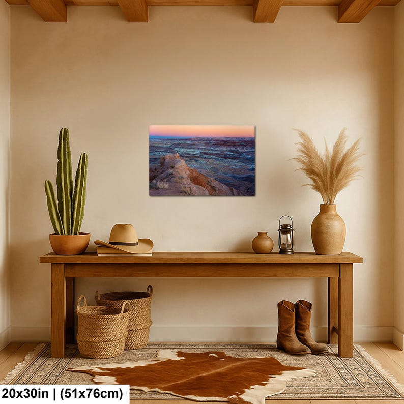 May include: A rectangular landscape wall art print featuring a desert canyon at sunset with orange, pink, and blue hues. The print measures 20 by 30 inches and is displayed on a beige wall above a wooden console table with decor items.