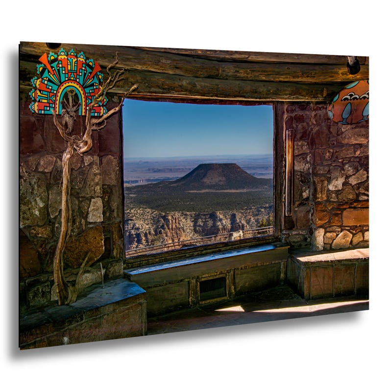 May include: A rectangular wall art print featuring a stone-walled interior view looking out through a large window at a distant flat-topped mountain. The scene includes a decorative colorful geometric wall hanging and a gnarled wooden branch.