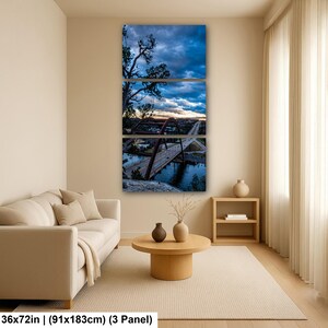 May include: A three-panel wall art set depicting a bridge over water at twilight. The image features a dark blue cloudy sky, a red arched bridge structure, and a road with vehicles. The total dimensions are 36 by 72 inches for the three panels.