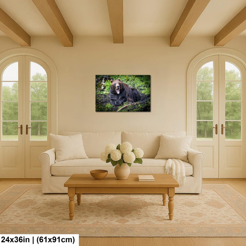 May include: A rectangular wall art print featuring a brown bear resting in a lush green forest setting with its mouth open. The artwork is displayed on a wall above a beige sofa, measuring 24 inches by 36 inches as indicated by the text.