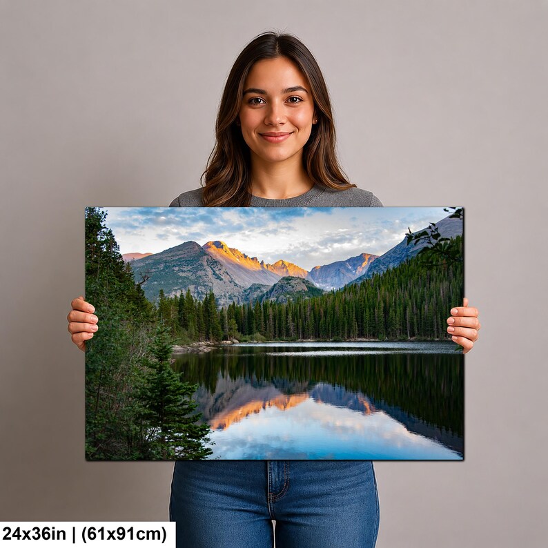 May include: A rectangular landscape wall art print measuring 24 by 36 inches, featuring a scenic mountain range with golden sunlight hitting the peaks, a dense forest of evergreen trees, and a calm lake reflecting the sky and mountains.