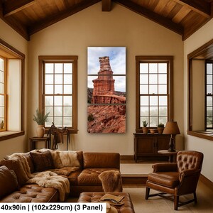 May include: A three-panel wall art set depicting a tall red rock formation against a cloudy sky. The artwork measures 40 by 90 inches. The panels feature layered sandstone textures in shades of rust, orange, and brown, showcasing a desert landscape.
