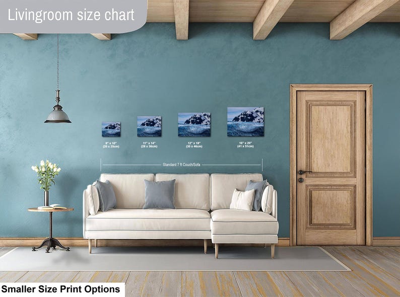 May include: A living room size chart displaying four rectangular wall art prints of a snowy mountain landscape above a cream-colored sectional sofa. The prints are labeled with dimensions in inches and centimeters: 8x10, 11x14, 12x18, and 16x20 inches.