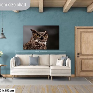May include: A rectangular wall art print featuring a detailed close-up of a brown and white great horned owl with piercing yellow eyes. The print is displayed above a cream-colored sectional sofa, with text indicating a 40x60 inch size.