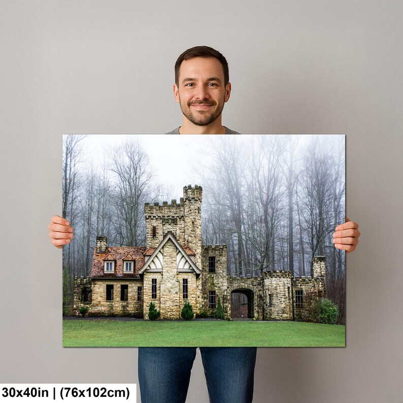 Op de afbeelding: Een rechthoekige wandkunstprint met een stenen kasteel met een roodbruin dak, tegen een achtergrond van hoge, bladloze bomen in een mistig bos. De print meet 76 bij 102 cm en toont een groen gazon op de voorgrond.