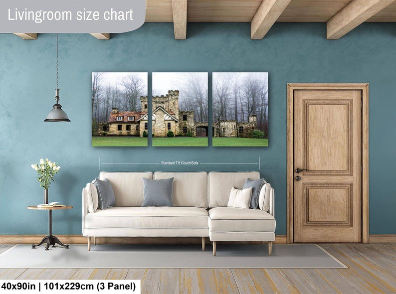 Op de afbeelding: Een driedelige canvas wandkunstset met een stenen kasteel in een mistig bos, weergegeven boven een cr&egrave;mekleurige hoekbank. De tekst Livingroom size chart en 40x90in | 101x229cm (3 Panel) is zichtbaar in de afbeelding.