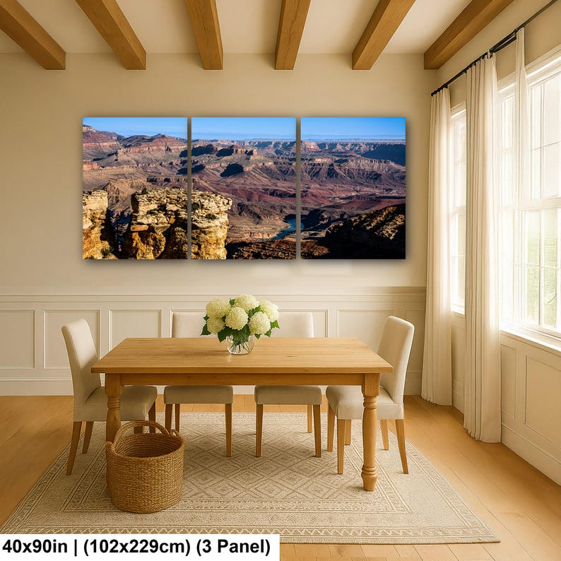 May include: A three-panel wall art set depicting a panoramic view of the Grand Canyon with layered rock formations, a winding river, and a clear blue sky. The artwork measures 40 by 90 inches in total, featuring deep red, brown, and blue tones.