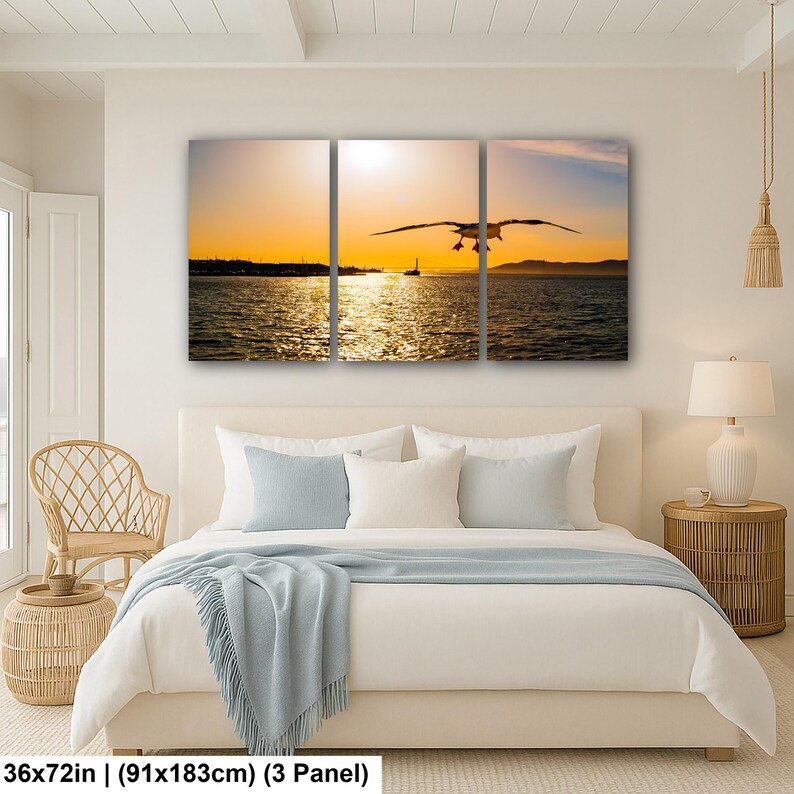 May include: A three-panel wall art set depicting a seagull in flight over a body of water during a golden sunset. The scene features a bright orange sky, a distant shoreline, and shimmering reflections on the water. The total size is 36x72 inches.