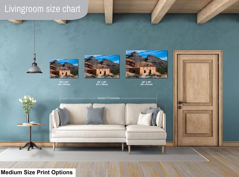 May include: A living room size chart displaying three landscape-oriented wall art prints of a desert adobe structure. The prints are labeled with dimensions of 16x24 inches, 20x30 inches, and 24x36 inches, shown hanging above a cream-colored sectional sofa.