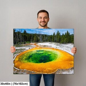 May include: A rectangular wall art print measuring 30 by 40 inches, featuring a vibrant landscape photograph of a geothermal hot spring with a deep green center surrounded by bright orange mineral deposits, set against a forest and blue sky.