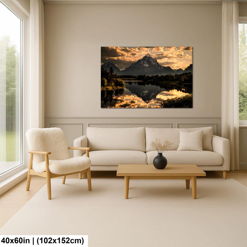 Puede incluir: Un cuadro rectangular de pared que muestra un paisaje de monta&ntilde;a al atardecer con nubes doradas y un reflejo en un lago tranquilo. La impresi&oacute;n mide 102 cm por 152 cm y se muestra sobre un sof&aacute; de color crema en una sala de estar.