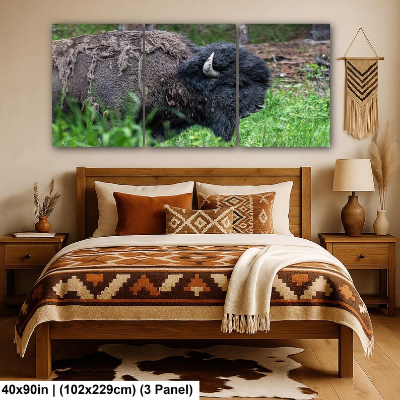 May include: A three-panel wall art set depicting a bison in a grassy field, displayed above a wooden bed frame with a brown patterned quilt, two orange pillows, and a cream throw blanket. The total dimensions are 40 by 90 inches.