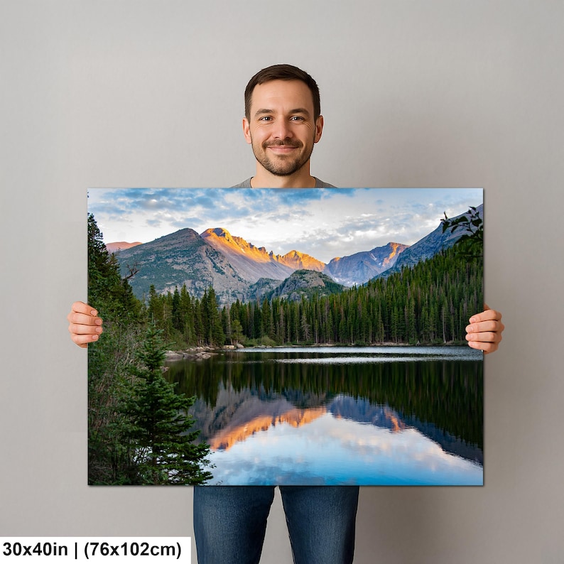 May include: A rectangular wall art print measuring 30x40 inches featuring a landscape photograph of a calm lake reflecting snow-capped mountain peaks at sunrise, surrounded by a dense forest of dark green pine trees under a cloudy sky.