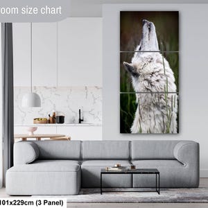 Pu&ograve; includere: Un set di arte murale a tre pannelli raffigurante un lupo bianco che ulula, esposto sopra un divano grigio. Il testo Livingroom size chart e 40x90in | 101x229cm (3 Panel) &egrave; visibile. Il lupo &egrave; mostrato di profilo su uno sfondo verde sfocato.