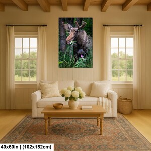 May include: A rectangular wall art print featuring a brown moose standing in a lush green forest, eating foliage. The moose has large antlers and is surrounded by tall grass and trees. The print dimensions are clearly labeled as 40x60 inches.