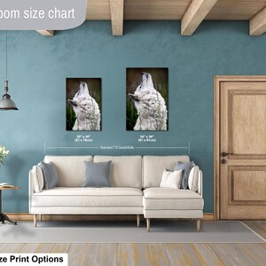 Pu&ograve; includere: Una tabella delle dimensioni per soggiorno che mostra due stampe artistiche verticali di un lupo bianco che ulula. Le stampe sono etichettate con dimensioni di 51 x 76 cm e 61 x 91 cm, posizionate sopra un divano angolare color crema in una stanza blu.