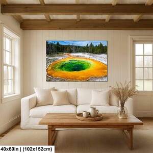 May include: A rectangular wall art print featuring a vibrant geothermal pool with a deep green center surrounded by bright orange and yellow mineral deposits, set against a backdrop of evergreen trees and a blue sky, measuring 40x60 inches.