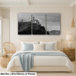 May include: A three-panel black and white canvas wall art set depicting a lighthouse perched on a rocky cliffside with a bridge structure in the background. The artwork measures 36 inches by 72 inches in total, featuring a cloudy sky and landscape.