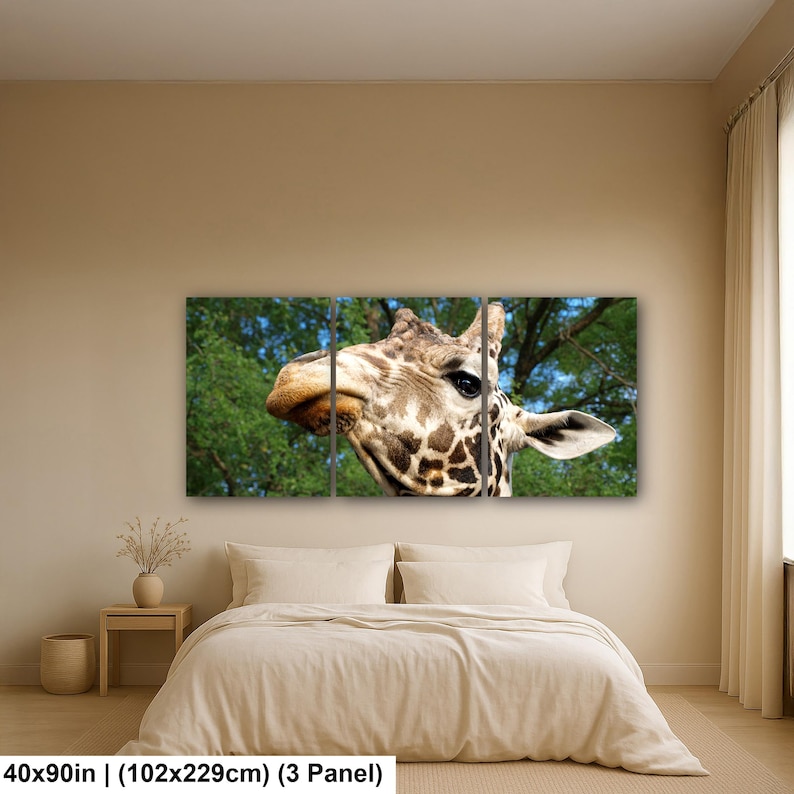 K&ouml;nnte beinhalten: Ein dreiteiliges Wandbild-Set mit einer Nahaufnahme eines Giraffenkopfes mit braunen Flecken vor einem gr&uuml;nen Laub-Hintergrund. Das Kunstwerk misst insgesamt 102 mal 229 cm und zeigt das Gesicht des Tieres, dunkle Augen und die gemusterte Haut.