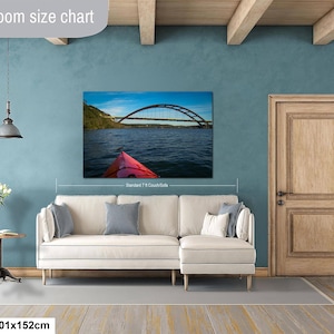 May include: A rectangular wall art print featuring a bridge over water and a red kayak bow, displayed above a cream-colored sectional sofa. The text Livingroom size chart appears at the top left, and 40x60in | 101x152cm is at the bottom left.