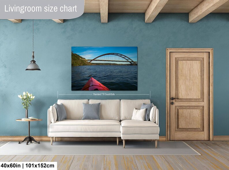 May include: A rectangular wall art print featuring a bridge over water and a red kayak bow, displayed above a cream-colored sectional sofa. The text Livingroom size chart appears at the top left, and 40x60in | 101x152cm is at the bottom left.