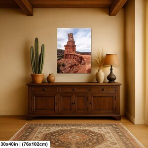 May include: A rectangular wall art print measuring 30 by 40 inches, featuring a tall, reddish-brown rock formation set against a cloudy sky. The landscape photograph displays layered geological strata and desert terrain in a vertical orientation.