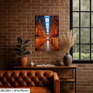 May include: A rectangular wall art print measuring 20 by 30 inches, featuring a perspective view of a multi-level prison cell block with orange metal railings and stairs, illuminated by a bright blue light source from the ceiling skylight.