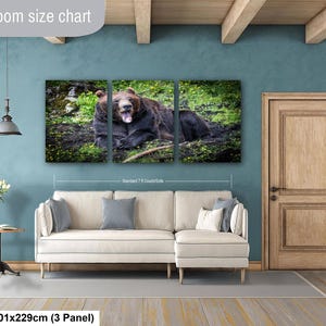 May include: A three-panel canvas wall art set featuring a brown bear yawning in a grassy field. The artwork is displayed above a cream-colored sectional sofa. The text "Livingroom size chart" and "40x90in | 101x229cm (3 Panel)" is visible.