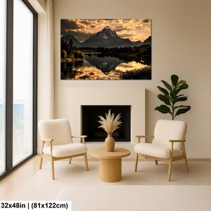 Puede incluir: Un cuadro rectangular que muestra un paisaje de monta&ntilde;a al atardecer con nubes doradas reflejadas en un lago tranquilo. La impresi&oacute;n mide 81 por 122 cm y se exhibe sobre una chimenea entre dos sillones de color crema y una planta.